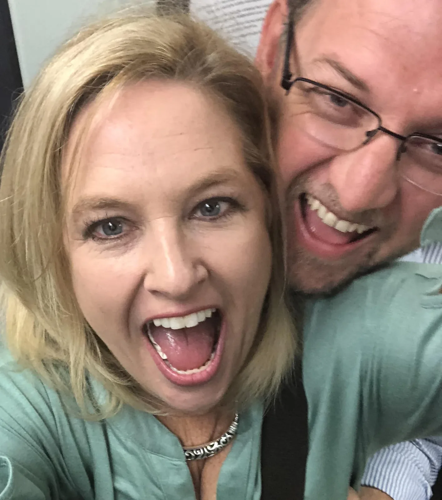 Playful close-up selfie of a laughing couple making excited faces together